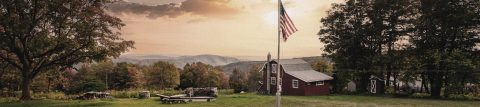 Two American flags blowing in the wind at sunset