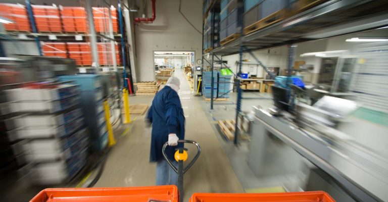 Blurred action shot of person in a warehouse setting pulling a pallet with a pallet truck